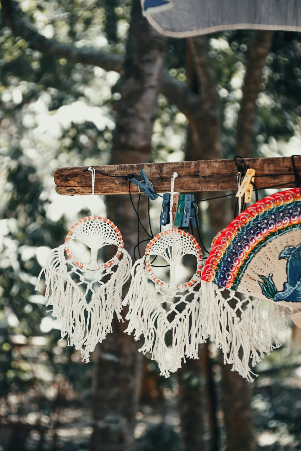 Macrame dreamcatchers and a patterned hand fan hang from wood.